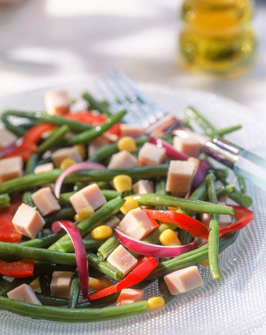 A summer salad with green beans, ham, peppers and corn