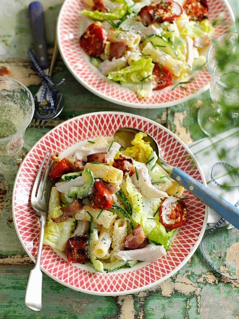 A pasta salad with rigatoni, chicken, tomatoes, lettuce and bacon