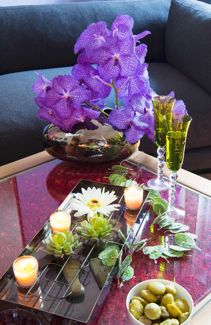 Dekoblumen-Arrangement mit Wasserschale und Teelichtern auf Couchtisch