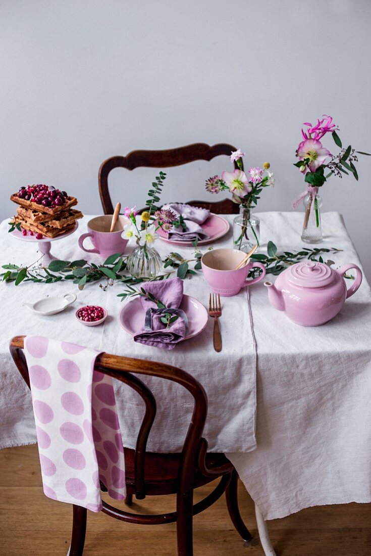 An Advent table set with Belgian spelt waffles, cherries, cranberries, pomegranate and Christmas roses