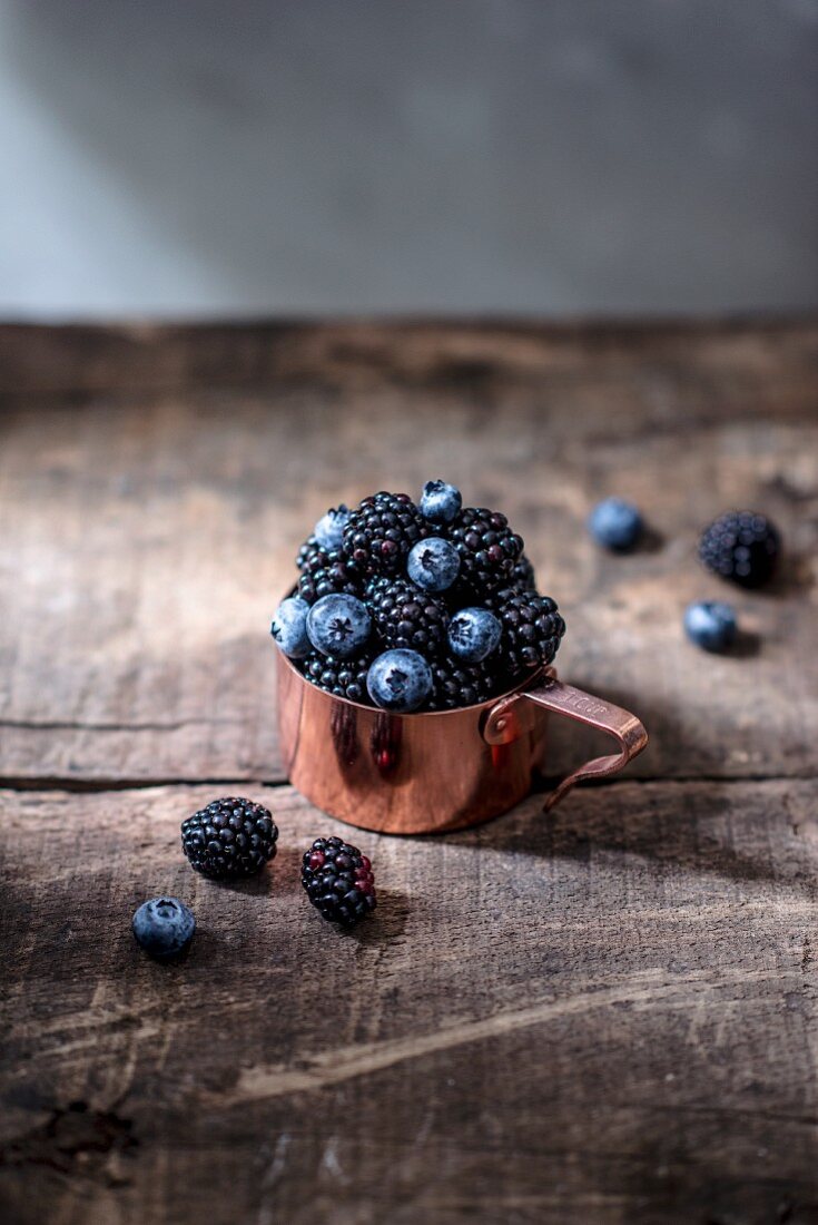 Blaubeeren und Brombeeren im Kupfermessbecher