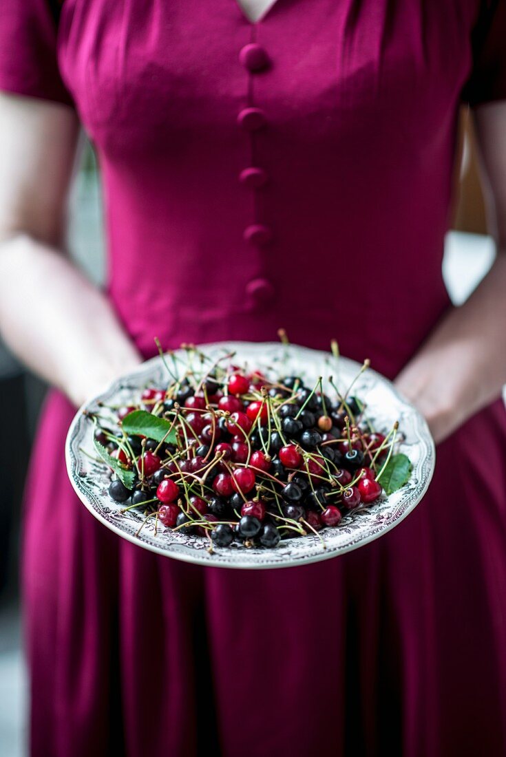 A woman holding a bowl of wild cherries