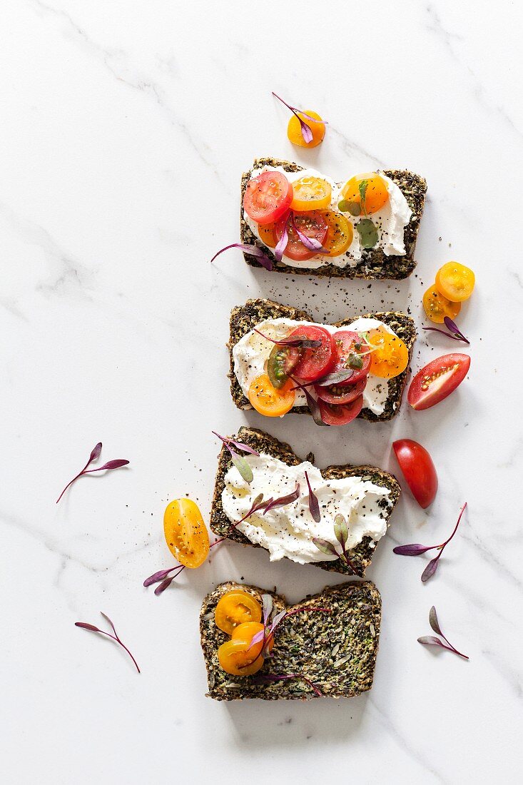 Four slices of cereal-free bread with fresh cheese and small tomatoes
