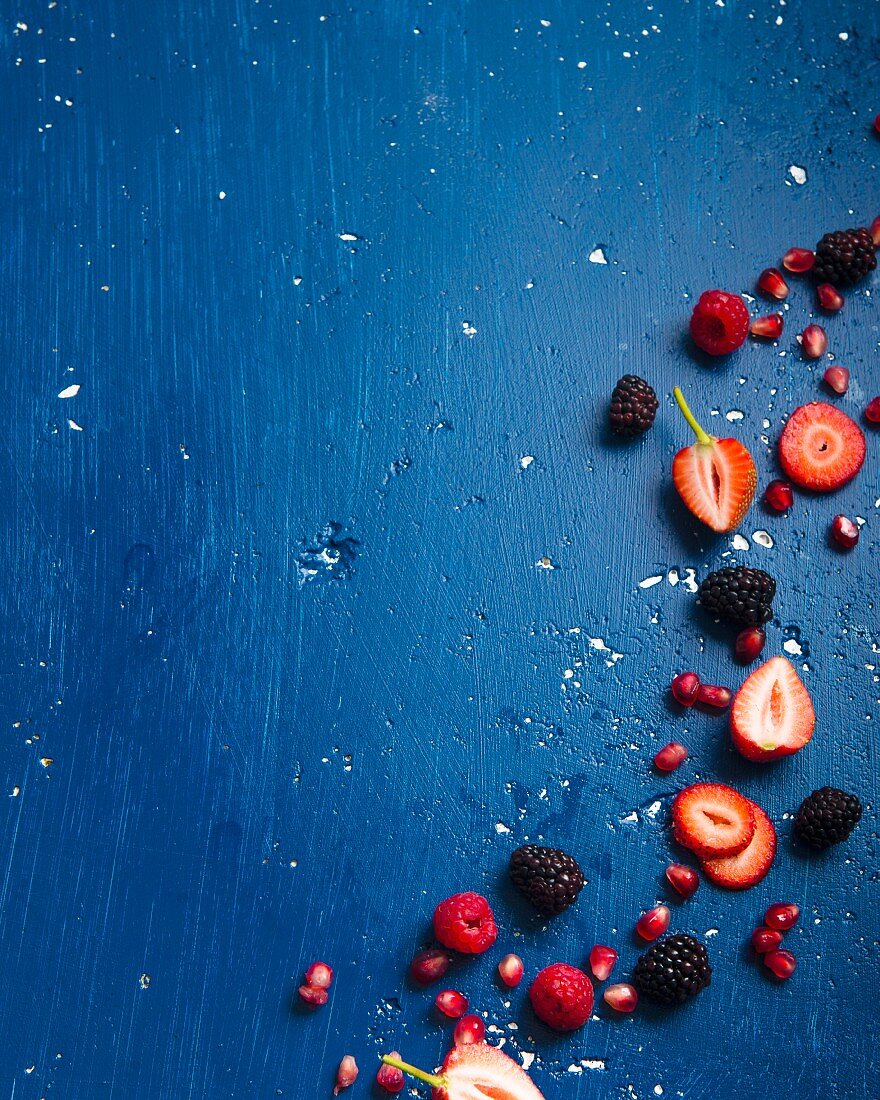 Various berries and pomegranate seeds on a blue background