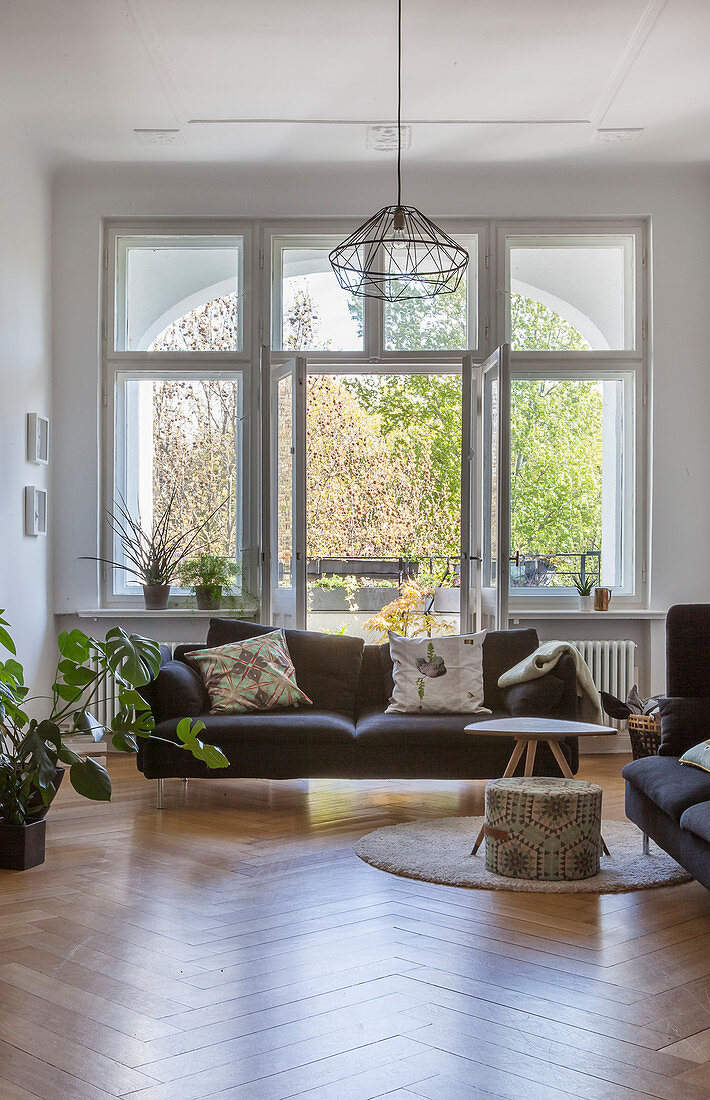 Sofa and coffee table in front of open balcony doors in period apartment