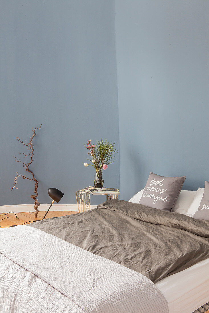 Doppelbett und Beistelltisch im Schlafzimmer mit blauer Wand