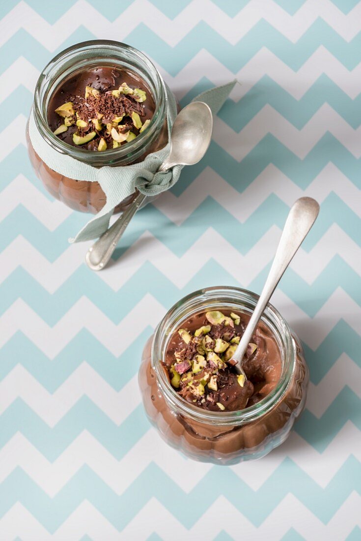 Two glasses of chocolate pudding with pistachios and spoons