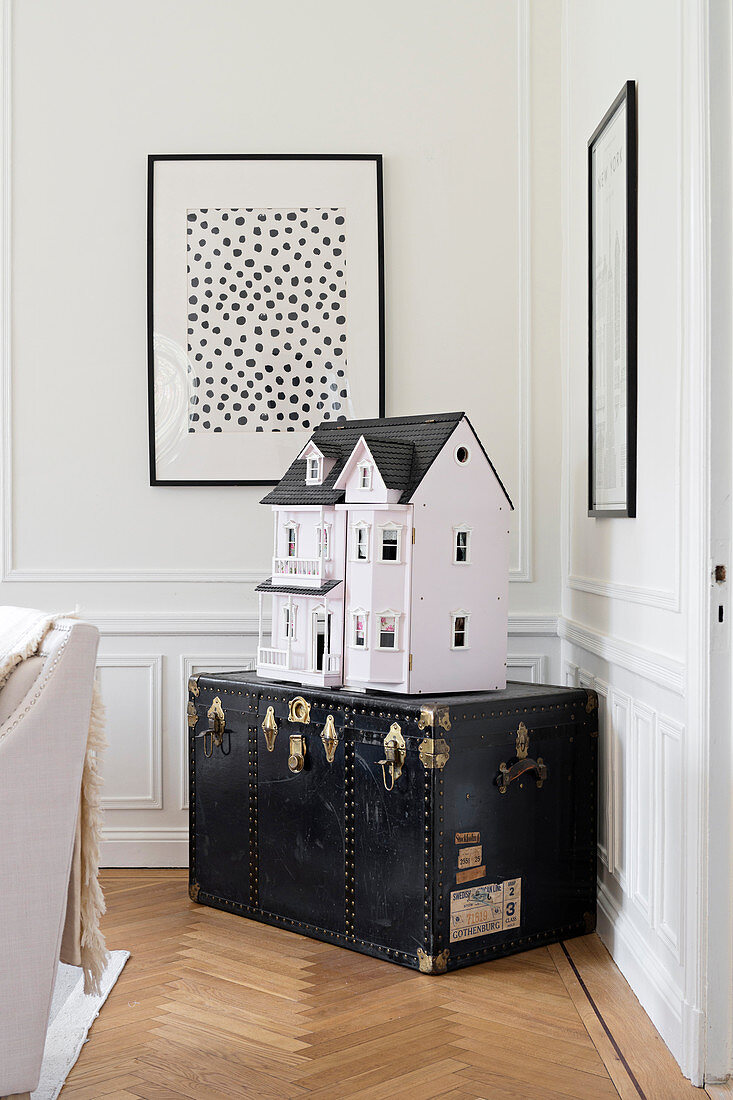 Dolls' house on old black trunk in corner