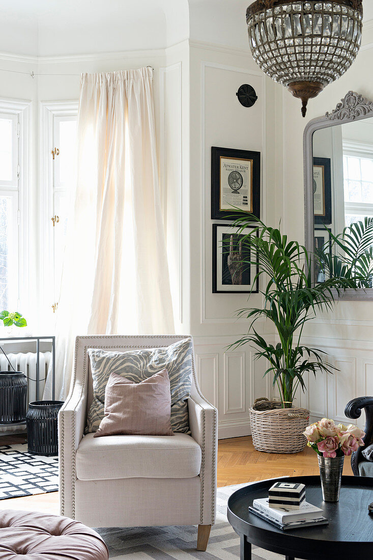 Pale armchair in elegant living room with panelled walls