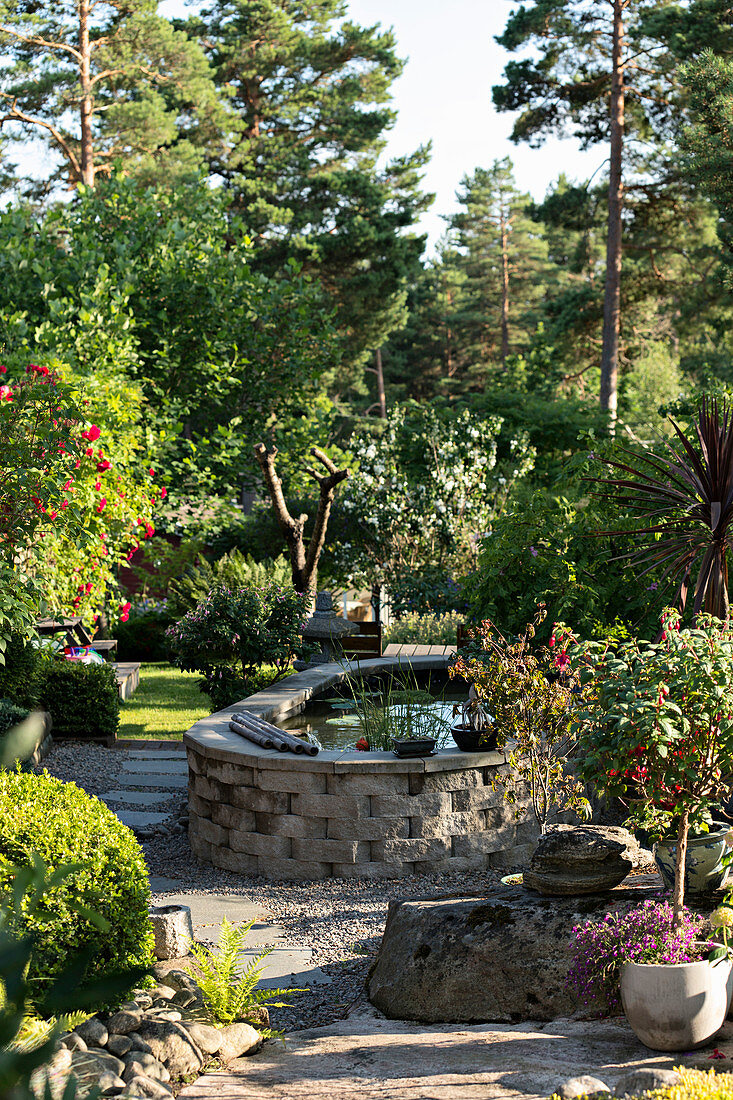 Raised pond with stone surround in garden