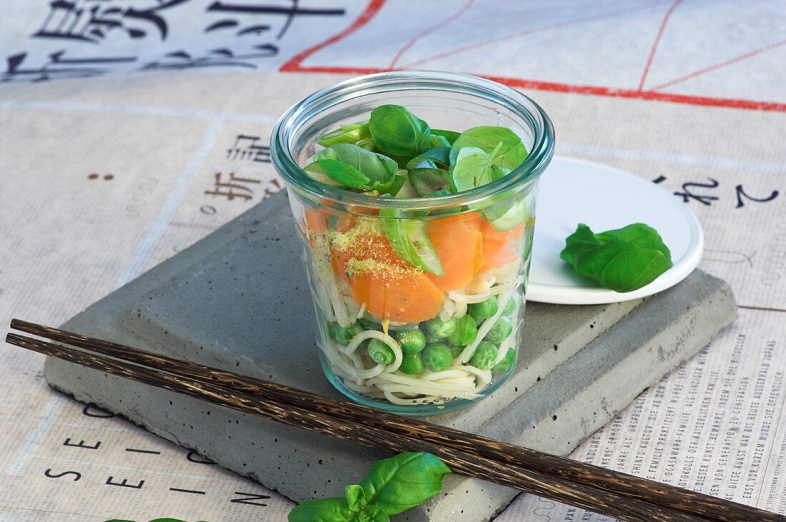 Zutaten für asiatische Nudelsuppe mit Gemüse in Glas geschichtet