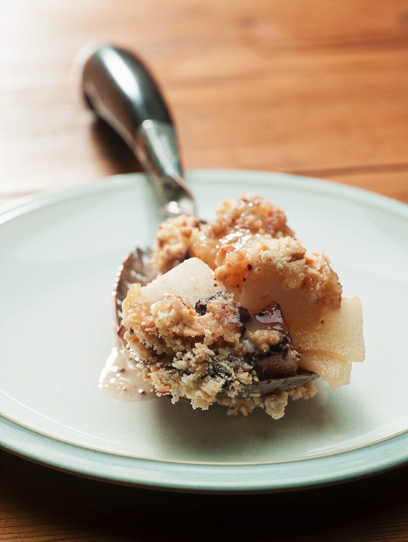 Crumble mit Birnen auf Löffel (Nahaufnahme)