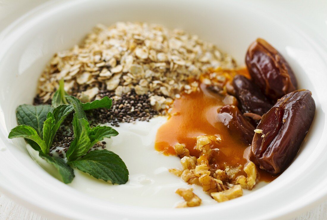 Yoghurt with dates, chia seeds, oatmeal, nuts, fruit sauce and mint