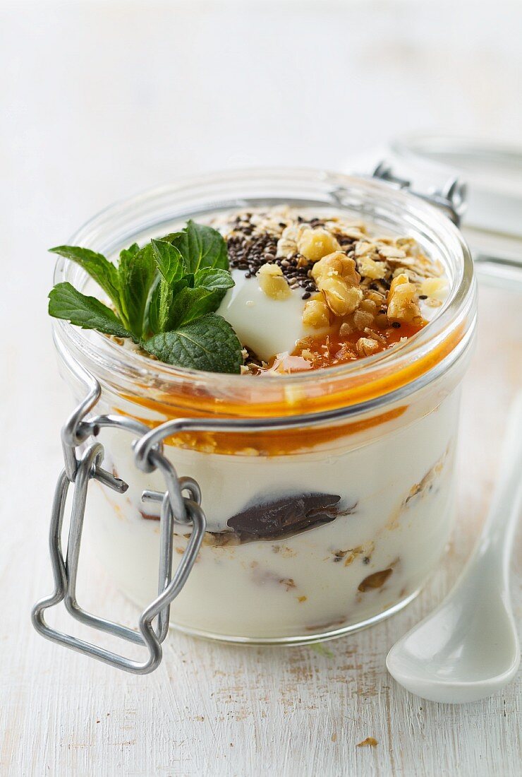 Yoghurt with chia seeds, dates, nuts, fruit sauce and mint in a mason jar