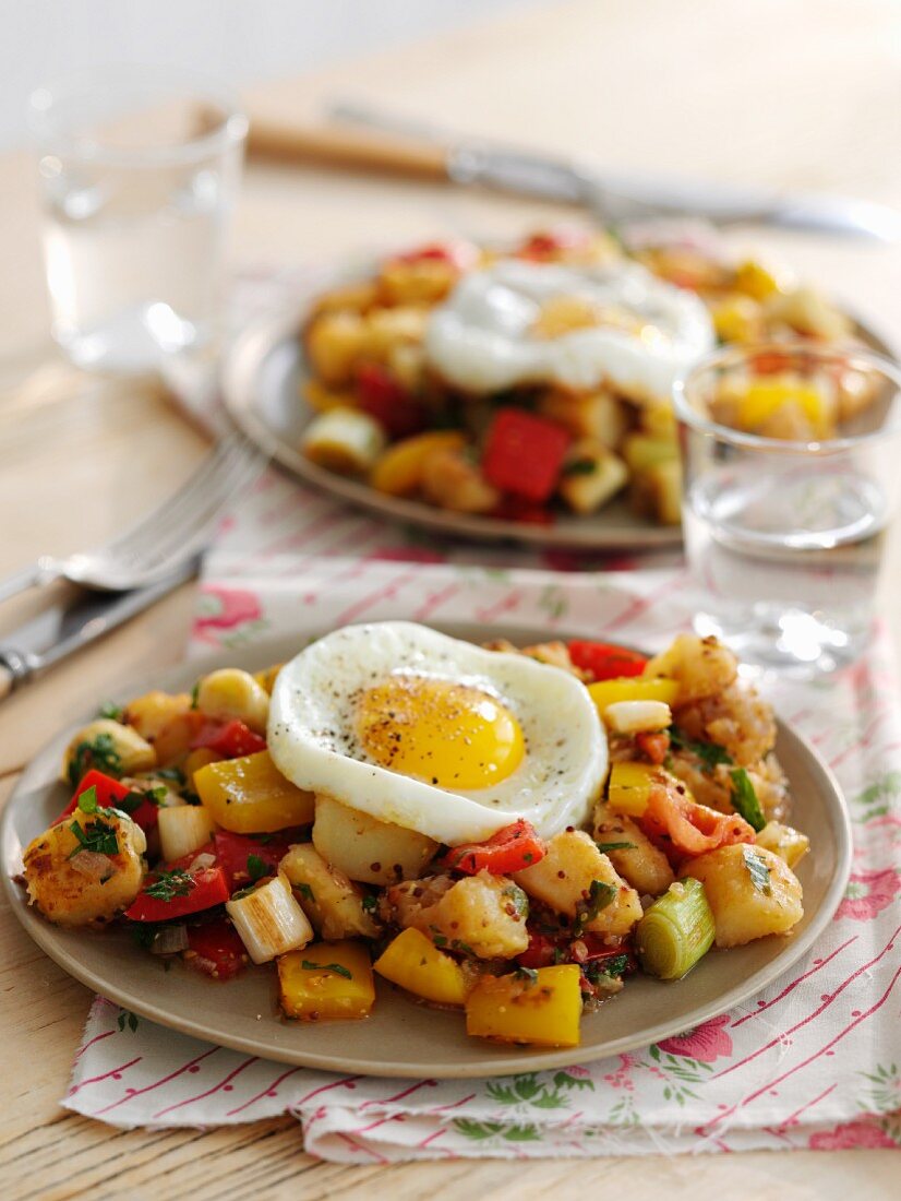 Fried potatoes with vegetables and fried eggs for brunch