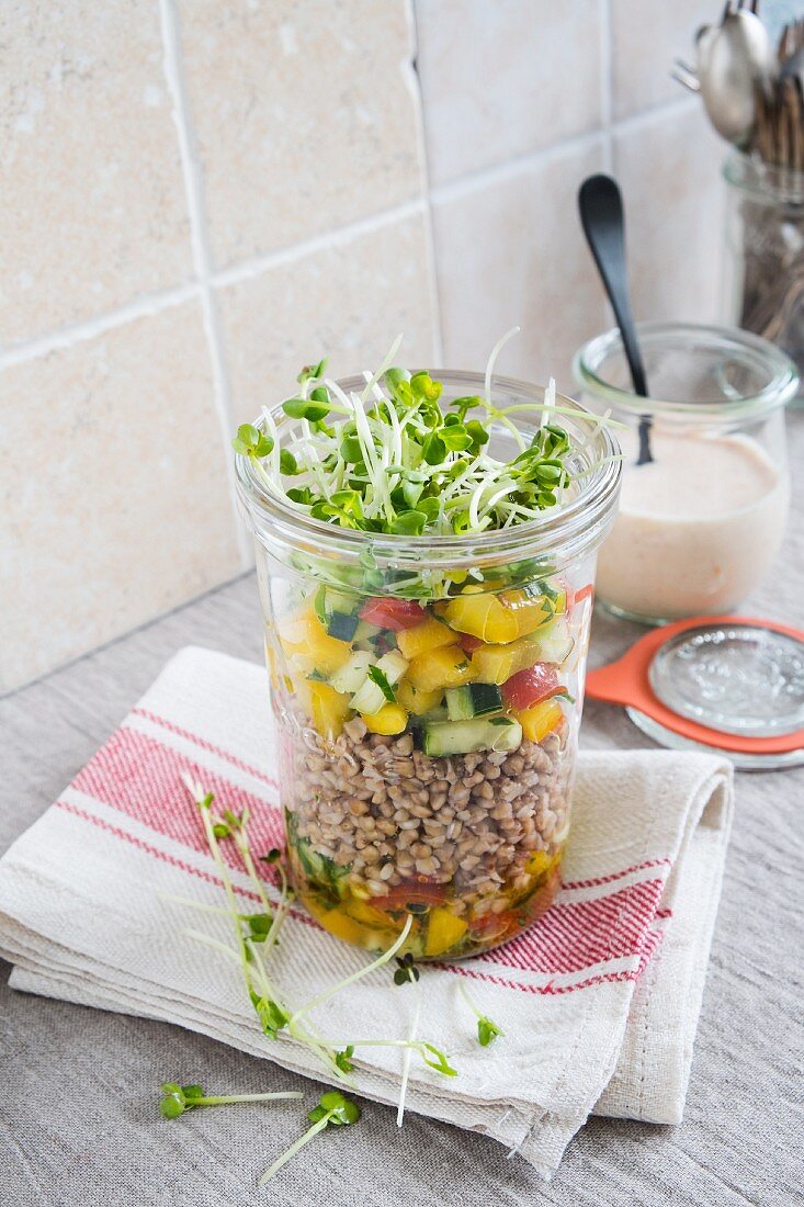 A buckwheat salad with vegetables and cress in a glass jar