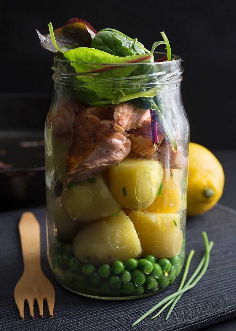 Steamed salmon and potatoes in a glass jar with peas and chard