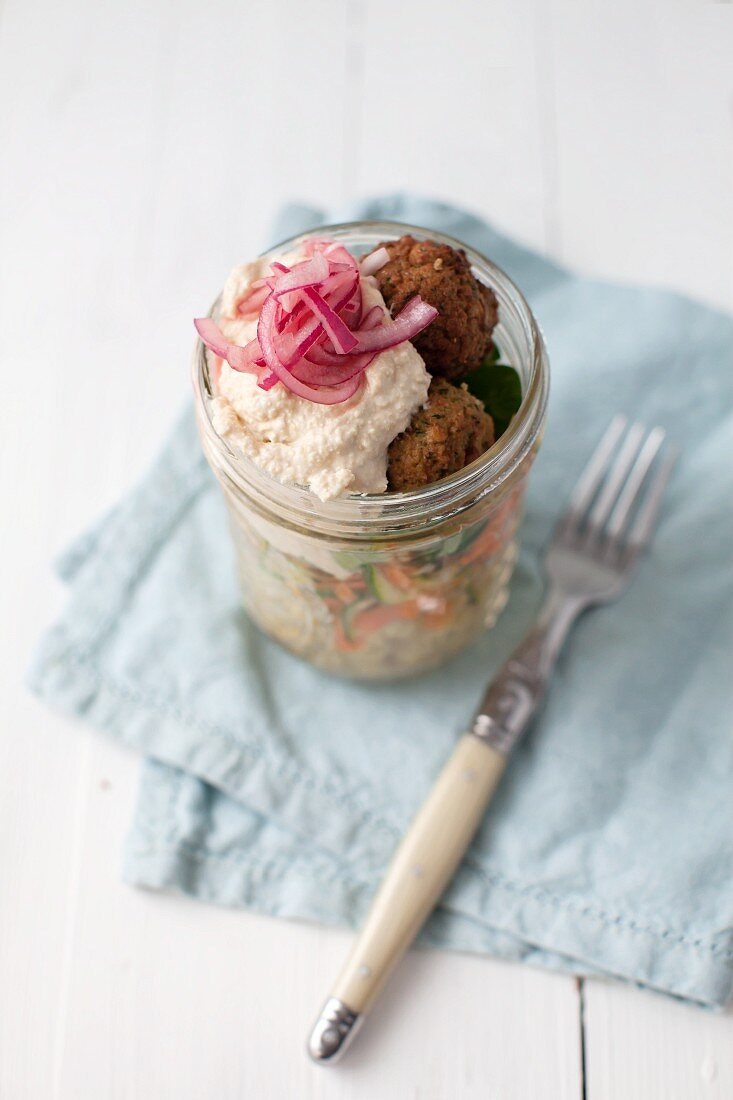 Veganer Couscoussalat mit Falafel, Karotten, Zucchini, Hummus und roten Zwiebeln