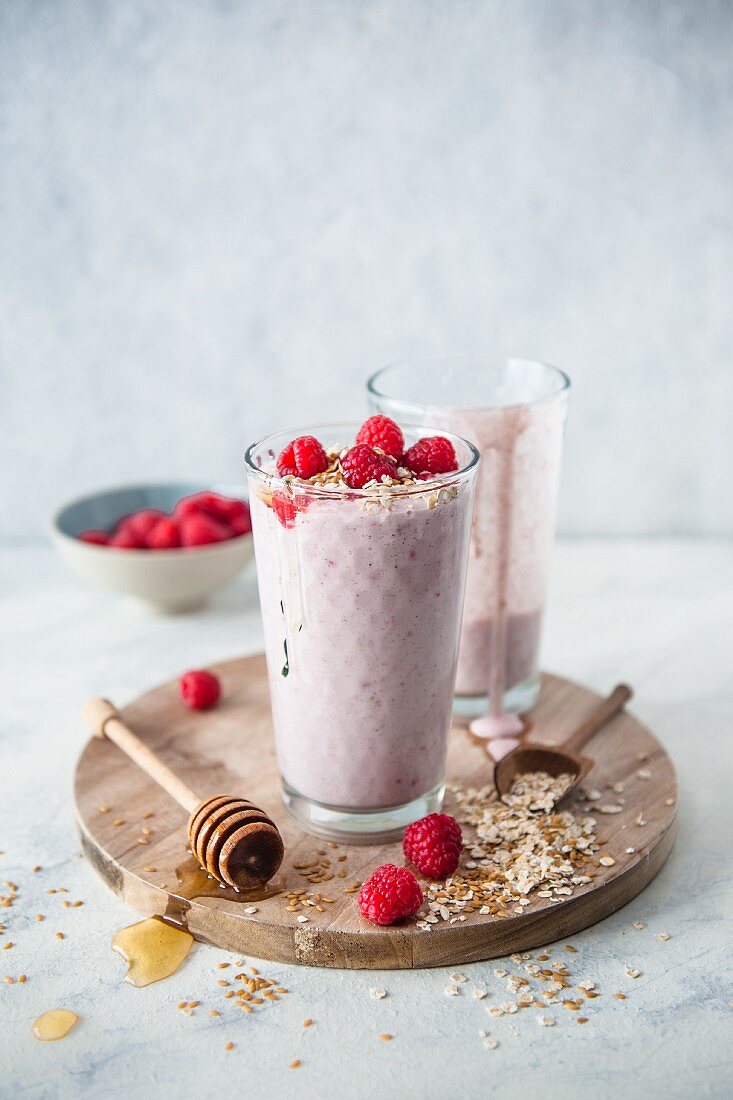 Breakfast smoothies with raspberries, yoghurt, milk, honey, oatmeal and linseed in glasses