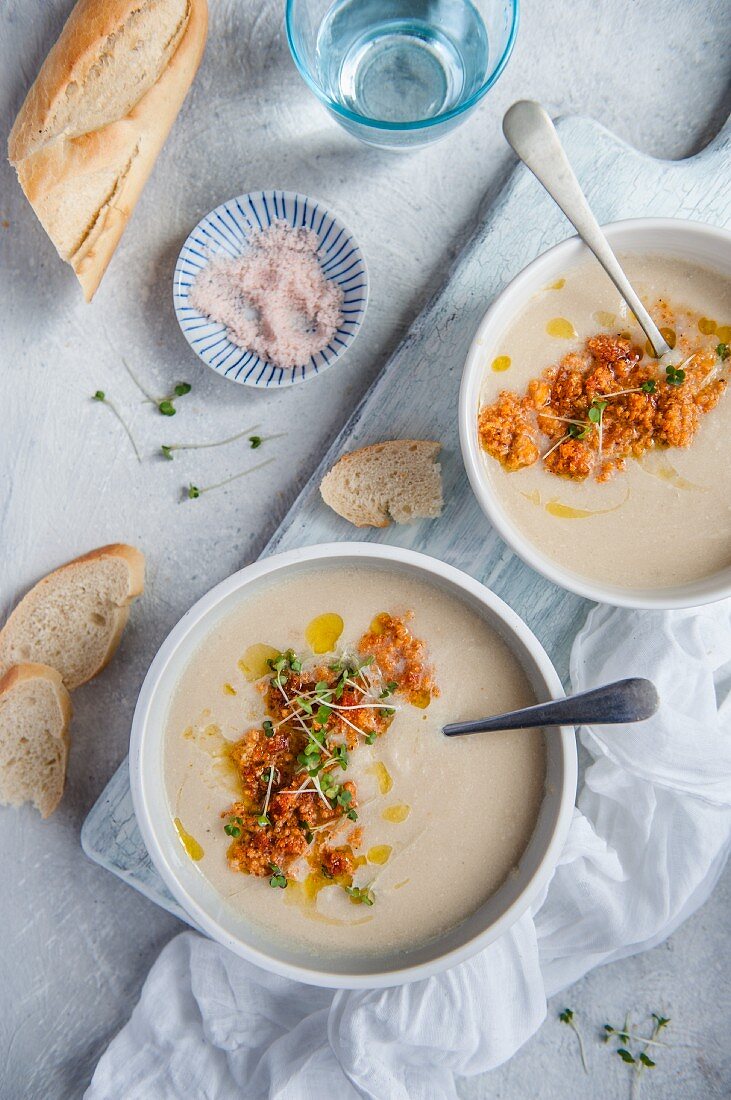 Cauliflower cream soup with chorizo ​​and olive oil, next to a piece of bread