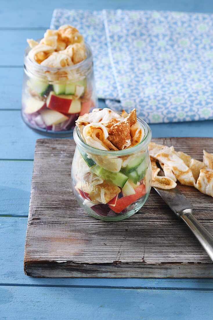 Apple and cucumber salad with pancake strips in a glass jar