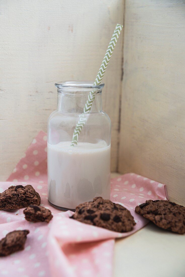 A plant-based drink in a glass bottle with vegan chocolate cookies next to it