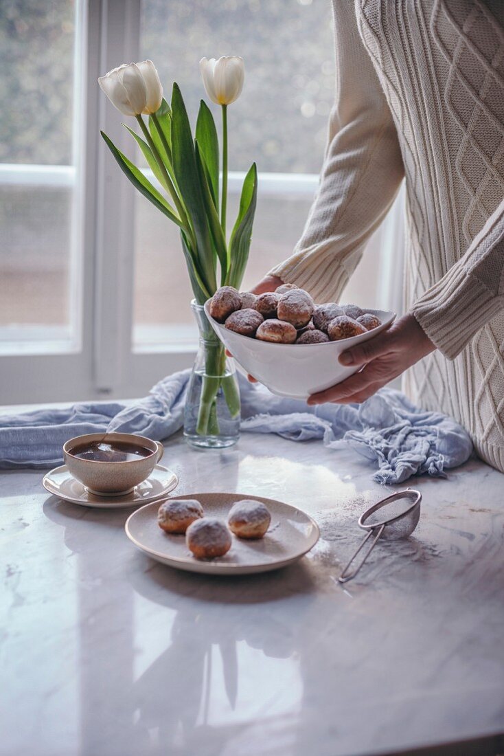 Woman holding a white bowl with Castagnole, Italian sweet fritters