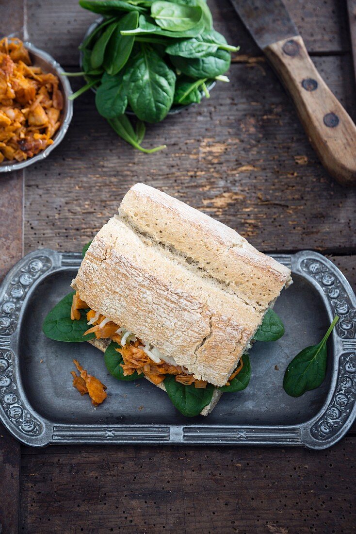 A vegan shredded jackfruit sandwich with spinach and cabbage