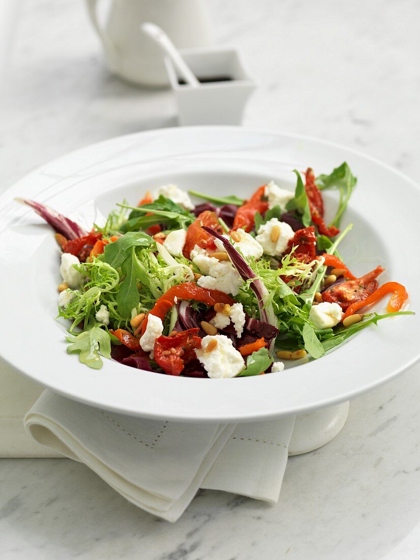 A mixed leaf salad with goat's cheese, peppers and pine nuts