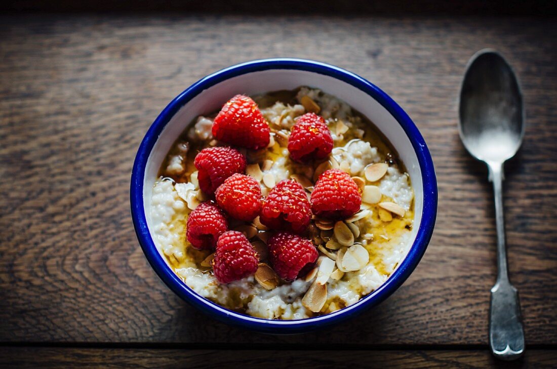 A bowl of porridge with fresh raspberries
