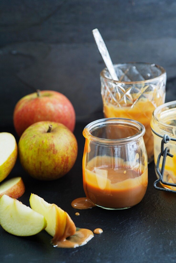 Caramel sauce in jam jars with whole and sliced apples
