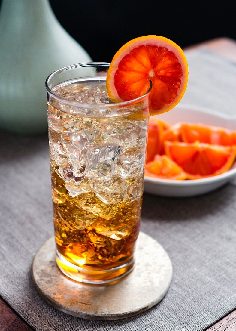 Spritzer in collins glass with ice and bloodorange garnish