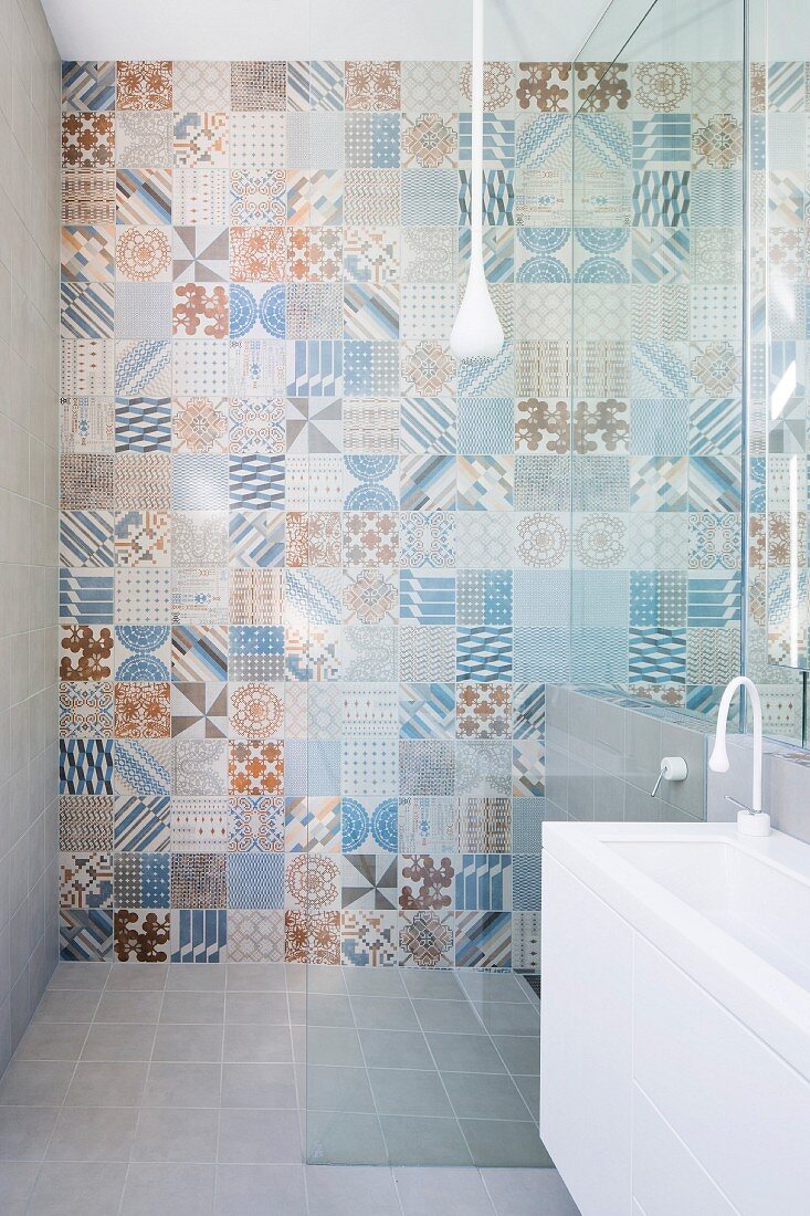 Various wall tiles with retro patterns in pastel blue and brown shades in shower area