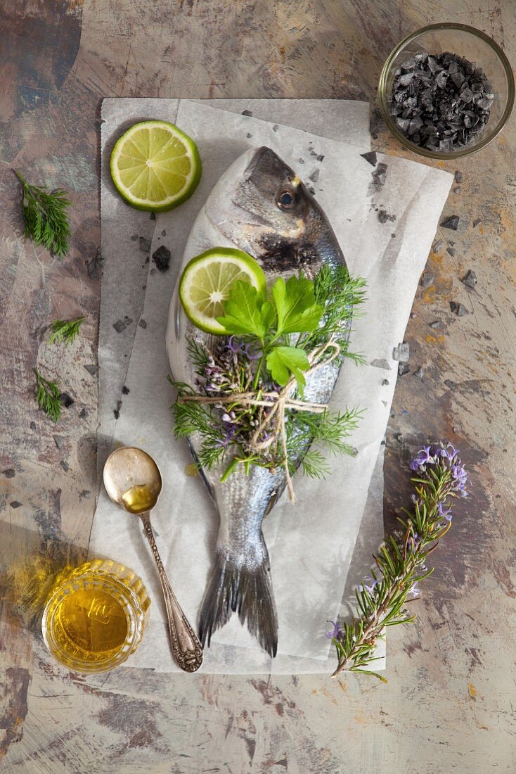 Frische Goldbrasse mit Kräutern und Limettenscheiben