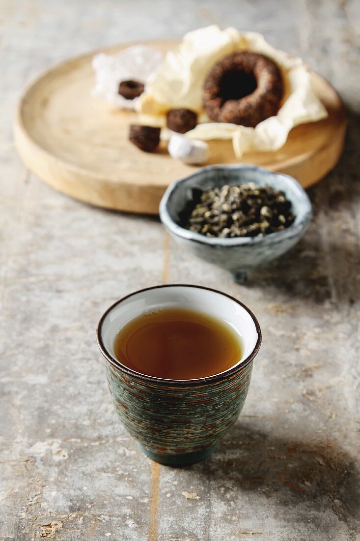 Tee in Porzellanschale und verschiedene Teeblätter (Asien)