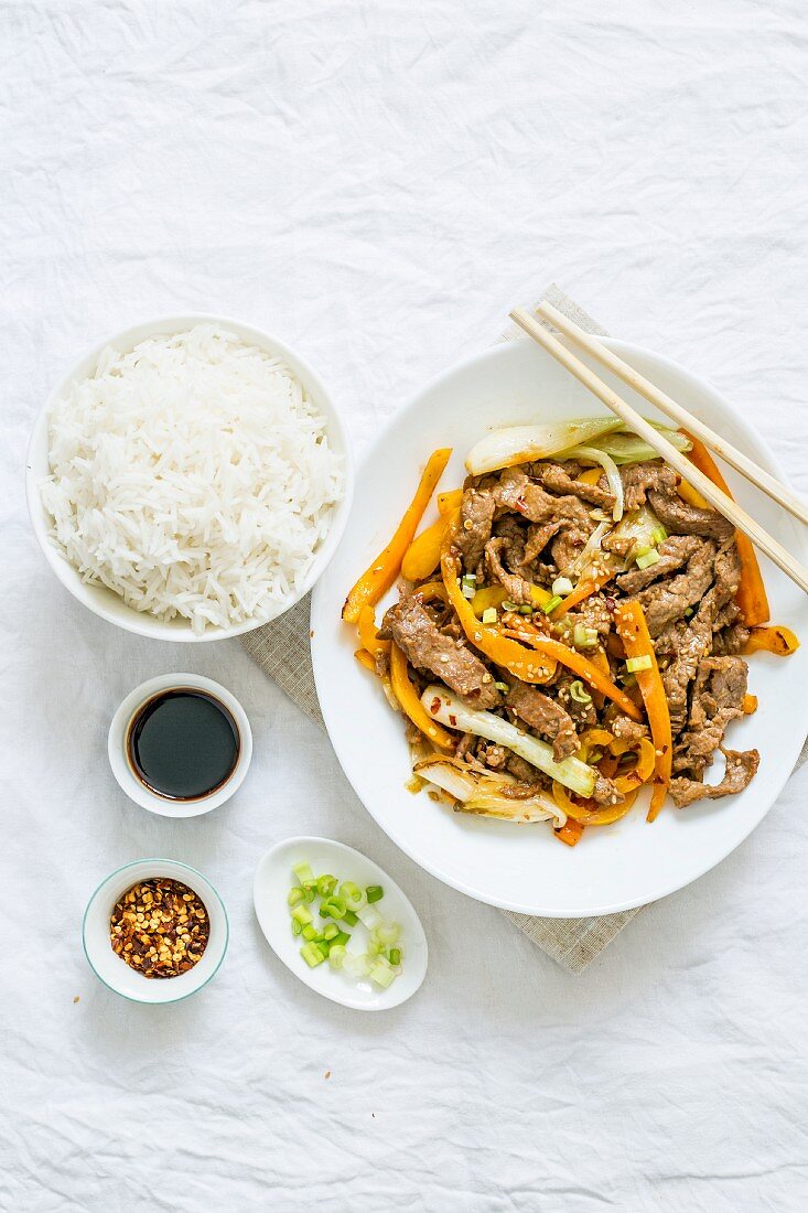 Stir Fry mit Rindfleisch, Karotten und Frühlingszwiebeln, dazu Reis (China)