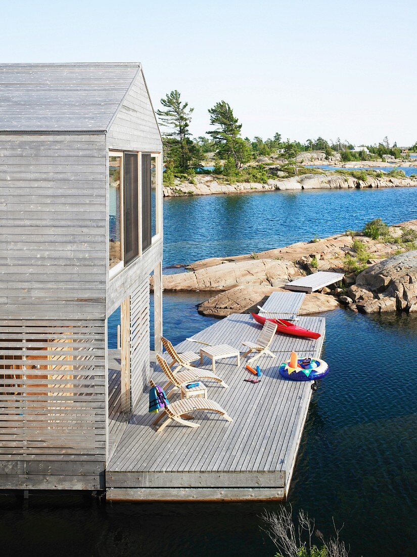 Outdoor furniture and kayak on wooden terrace of two-storey house