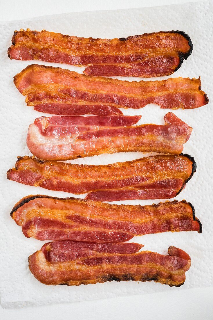 Fried slices of bacon on kitchen roll (seen from above)