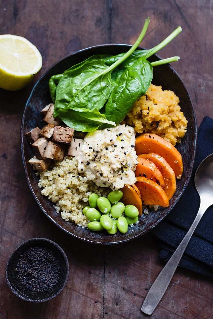 Buddha Bowl mit Quinoa, Linsen, Süsskartoffeln, Edamame, Tofu, Spinat und Hummus