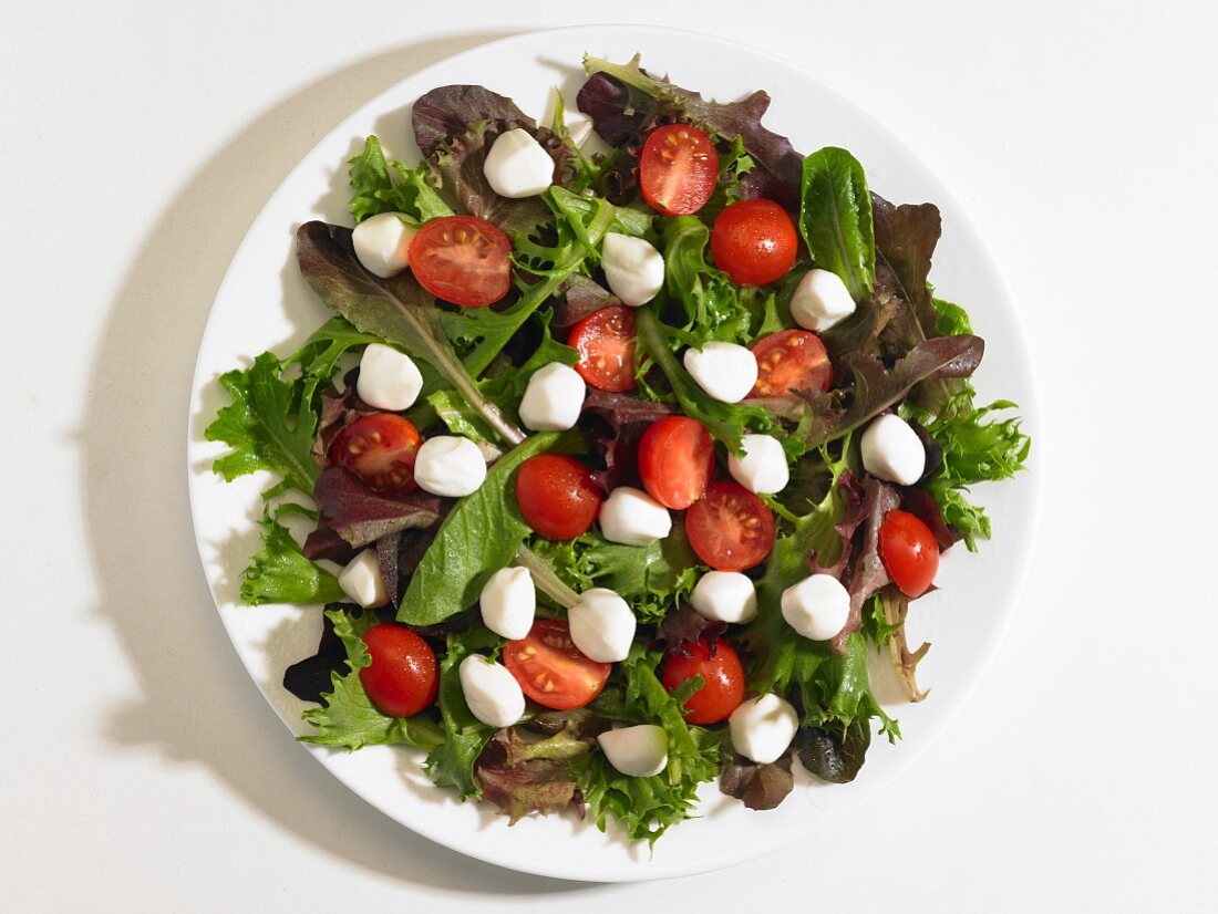 Cherry tomatoes and mini mozzarella balls on a bed of lettuce (seen from above)