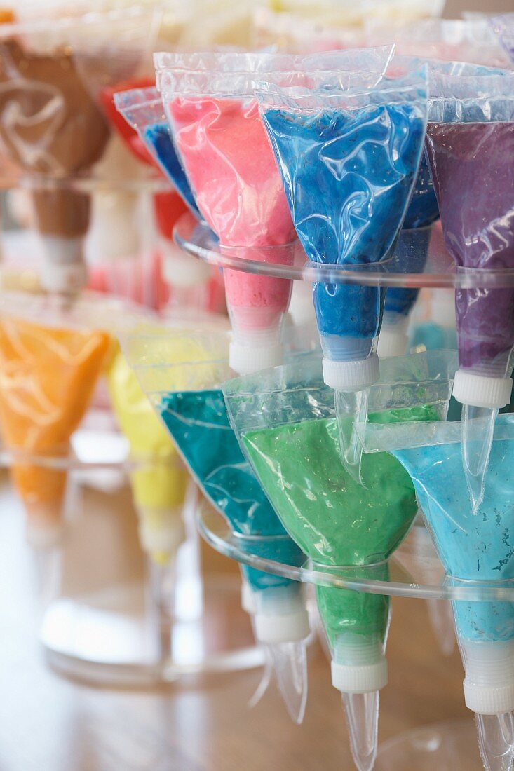 Verschiedenfarbige Zuckerdekore in Spritzbeuteln auf Ständern
