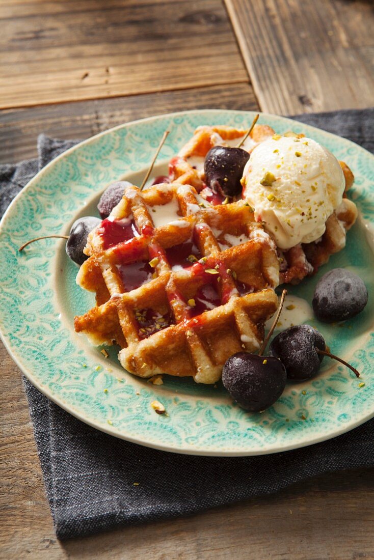 Runde belgische Waffeln mit Kirschen, Kirschsauce und Vanilleeis