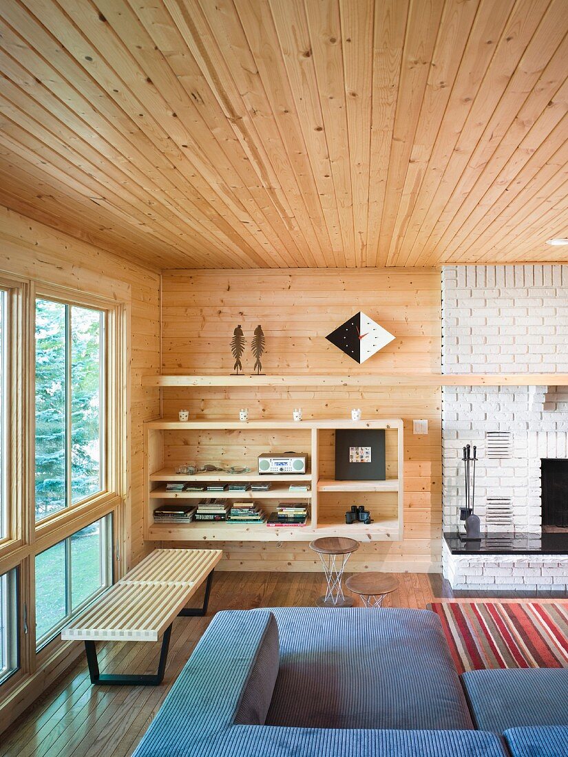 Lounge area with open-fronted shelves next to white brick chimney breast