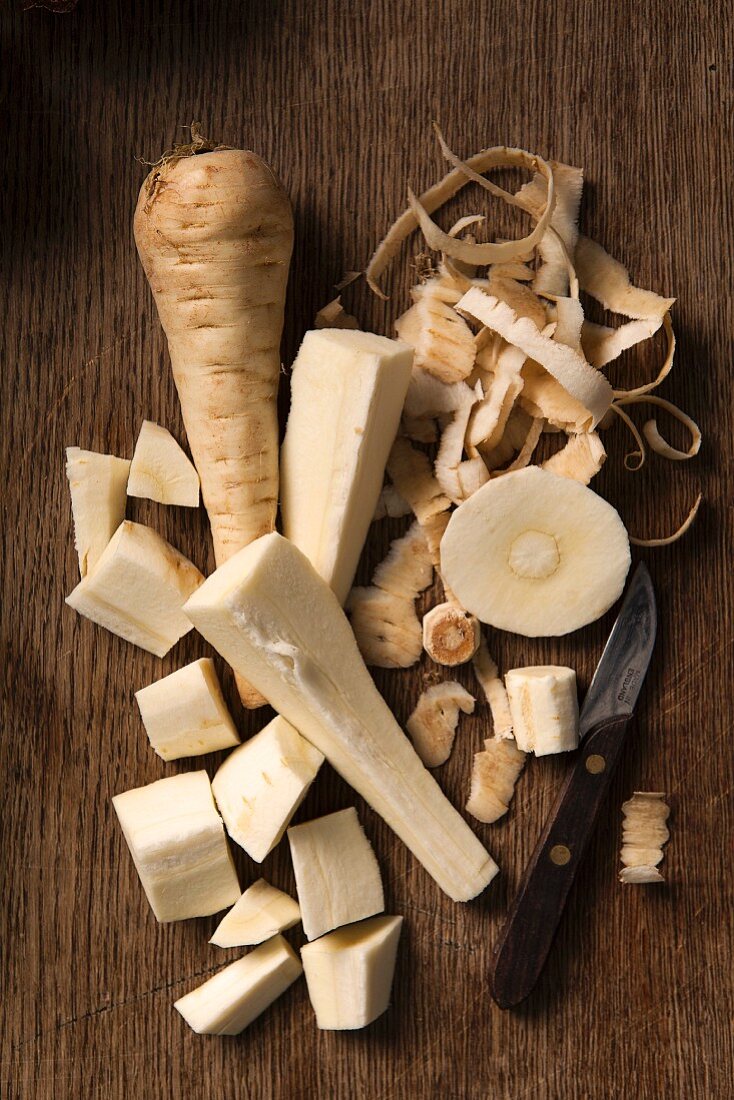 Parsnips, peeled and cut into sticks, on a wooden background