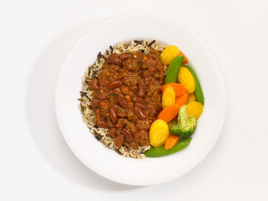 Low Fat Chili mit Gemüse und Reis auf Teller vor weißem Hintergrund (Aufsicht)