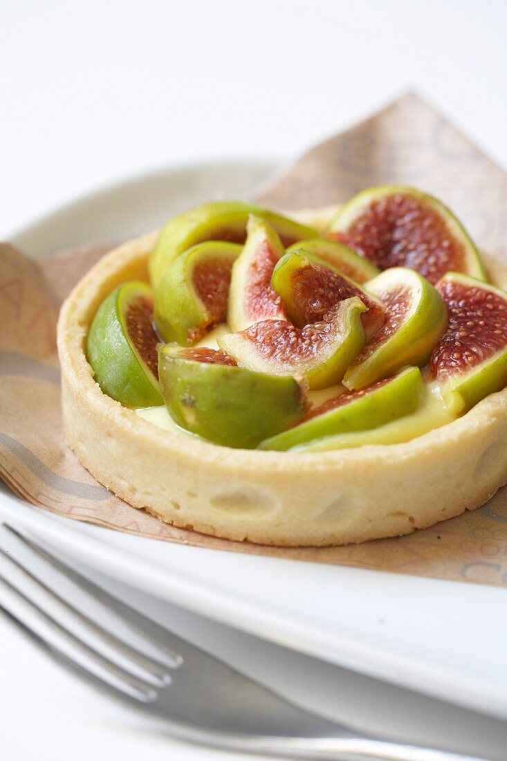 A fig tartlet on a plate with a napkin