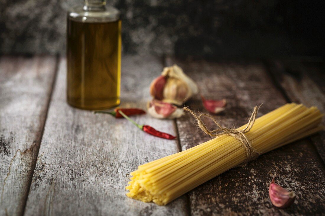 Stillleben mit Bündel Spaghetti, Chili, Knoblauch und Olivenölflasche