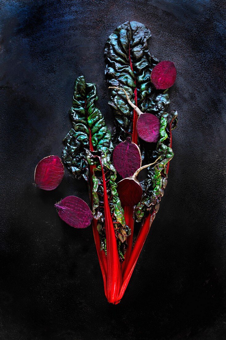 Red chard and beetroot halves in front of a black background