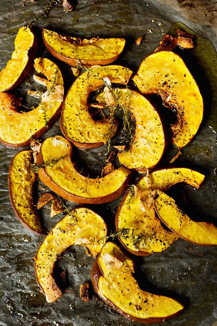 Grilled pumpkin slices with olive oil, garlic and thyme on an oven tray