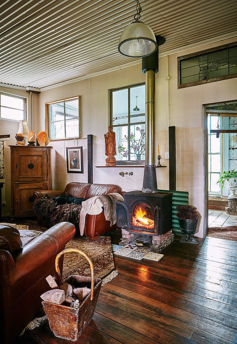 Fireplace with fire and vintage leather furniture in a converted stable